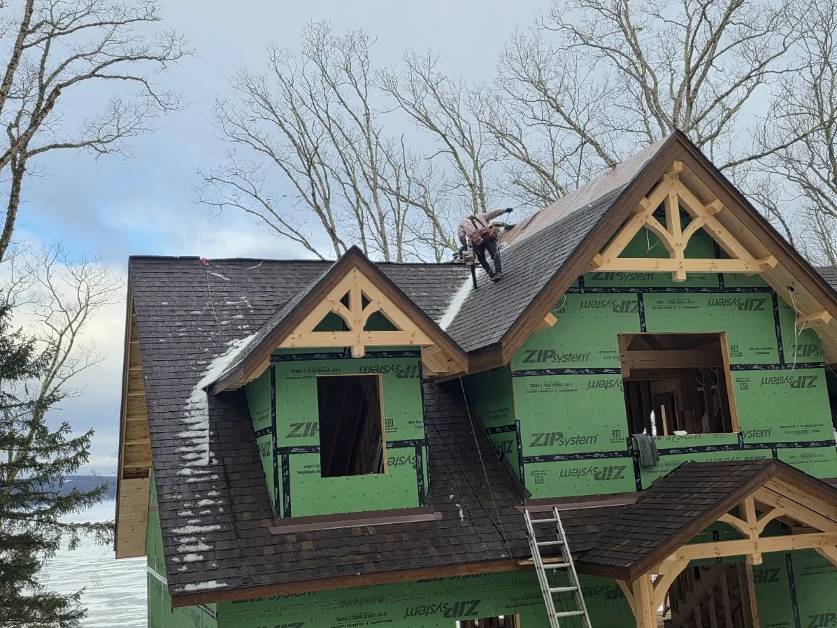 Roofer installing shingles on a snow-covered roof during a Pennsylvania winter